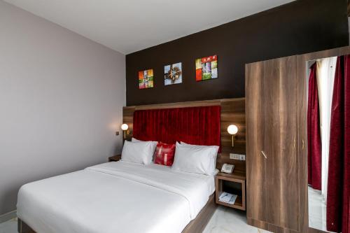 a bedroom with a large bed and a red curtain at Hotel Horizon Entebbe in Entebbe