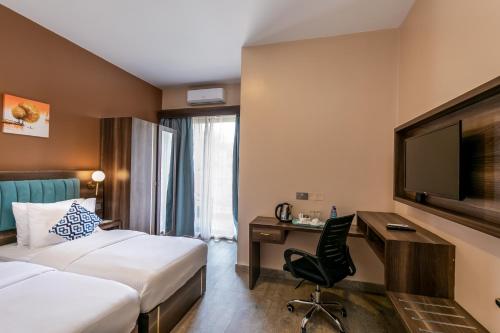 a hotel room with two beds and a desk and a tv at Hotel Horizon Entebbe in Entebbe