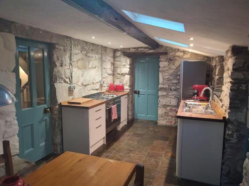 uma cozinha com portas azuis e uma parede de pedra em Y Cwtch - Panoramic mountain views within Snowdonia's National Park em Dolgellau