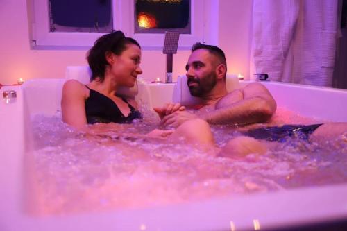 Ein Mann und eine Frau sitzen in einer Badewanne in der Unterkunft Love room Unique - Sauna / Jacuzzi in Charleville-Mézières
