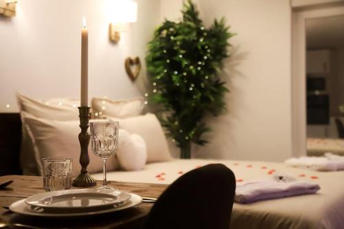 a table with a candle and a plate on a table with a christmas tree at Love room Unique - Sauna / Jacuzzi in Charleville-Mézières