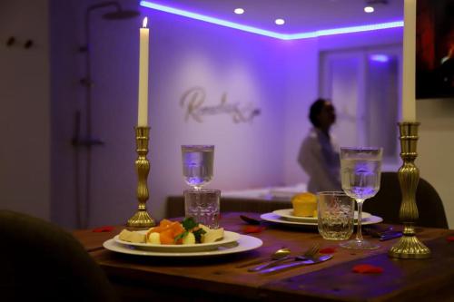 a table with a candle and plates of food on it at Love room Unique - Sauna / Jacuzzi in Charleville-Mézières