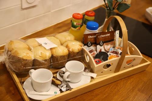 a tray filled with bread and cups on a table at Love room Unique - Sauna / Jacuzzi in Charleville-Mézières