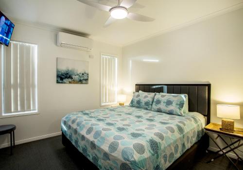 a bedroom with a bed and a table and two windows at 3 Seacrets at Shelly in Urangan