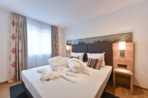 - une chambre avec un grand lit blanc et des serviettes dans l'établissement Monusse Boid Wohnung 6, à Pfronten