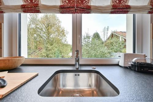 eine Küchentheke mit Spüle und zwei Fenstern in der Unterkunft Monusse Boid Wohnung 11 in Pfronten