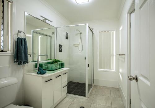 a white bathroom with a shower and a sink at 3 Seacrets at Shelly in Urangan
