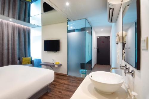 a bathroom with a bed and a sink in a room at Apple Hotel Times Square in George Town