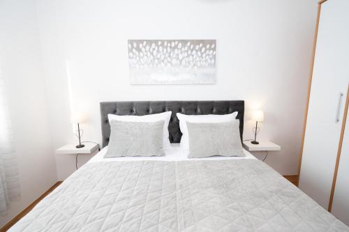a white bedroom with a large bed with white pillows at The Oasis in Trilj