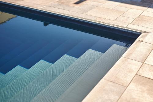 a swimming pool with blue water and tile floors at Borgo della Spiga - Adult Friendly Country House in Cervidone