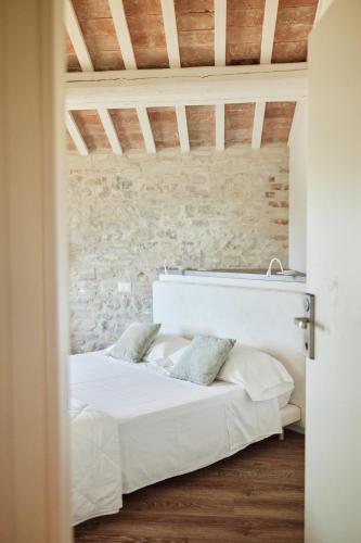 a bedroom with a white bed with a stone wall at Borgo della Spiga - Adult Friendly Country House in Cervidone
