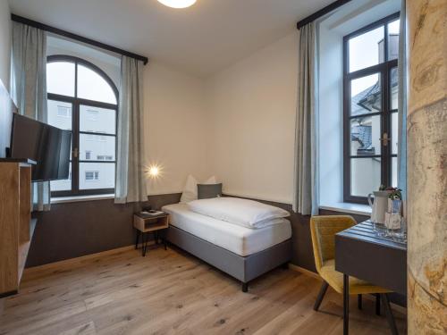 a hotel room with a bed and two windows at Kirchenwirt Wörgl in Wörgl