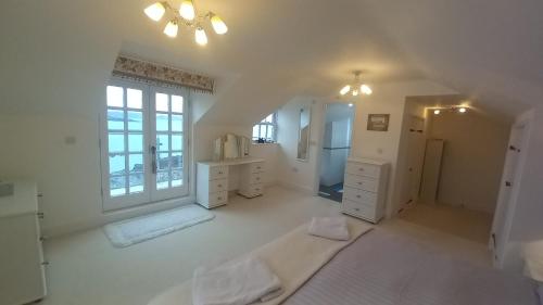 een grote witte kamer met witte meubels en een raam bij Quayside in Porthscatho
