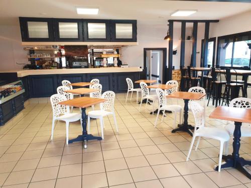 un restaurant avec des tables en bois et des chaises blanches dans l'établissement Coliwork Le Saint Romain, à Dangé
