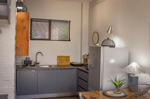 a kitchen with a refrigerator and a table in it at Dragon Tree in Yzerfontein