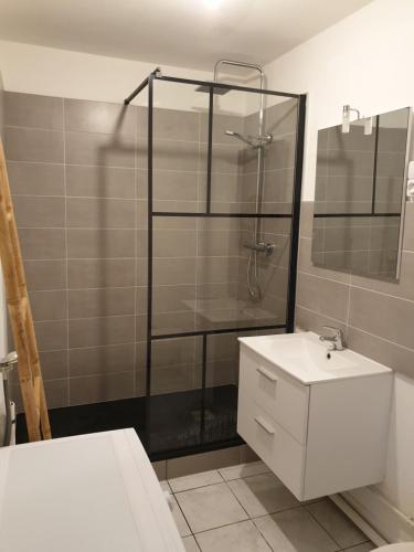 La salle de bains est pourvue d'une douche et d'un lavabo blanc. dans l'établissement Appartement plage de Trestraou, à Perros-Guirec