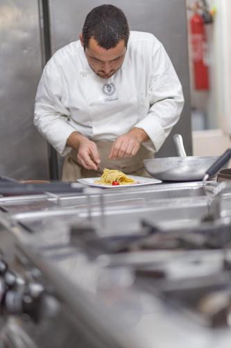 a chef preparing a plate of food in a kitchen at Country Hotel Residence Da Pilade in Capoliveri