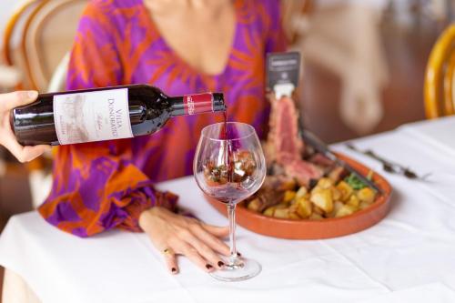 una mujer está vertiendo vino en una copa de vino en Country Hotel Residence Da Pilade, en Capoliveri