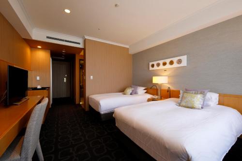 a hotel room with two beds and a television at Hotel Nikko Kanazawa in Kanazawa