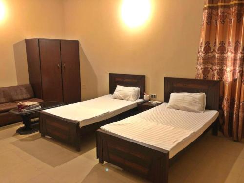 1 dormitorio con 2 camas y sofá en Babar House, en Faisalabad