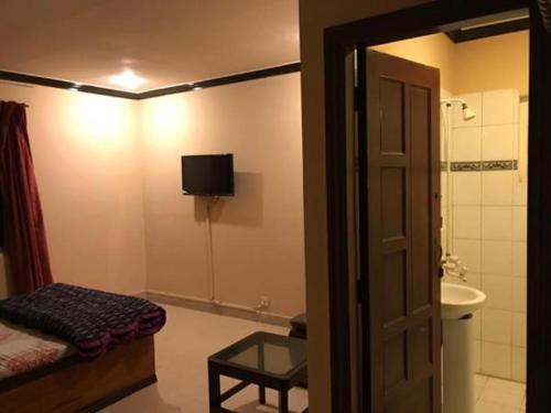 ein Badezimmer mit einem Waschbecken und einem TV an der Wand in der Unterkunft Babar House in Faisalabad