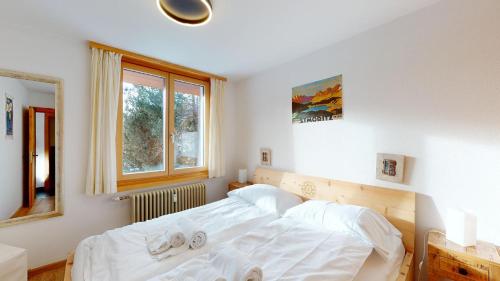 a bedroom with a bed with white sheets and a window at Rosatsch 14 in Surlej