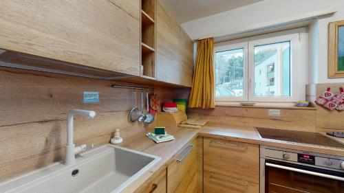 Una cocina con armarios de madera y un fregadero y una ventana. en Daniela B, en St. Moritz