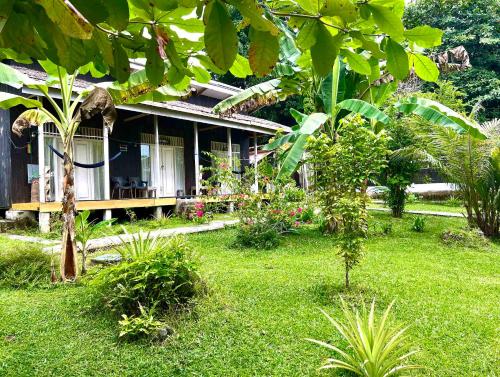 a house with a green yard with a grass yard at Sanctum Una Una Eco Dive Resort in Pulau Unauna