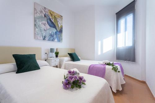 Dos camas en una habitación con flores púrpuras. en Ático Terrazas Piscina Parking 3 Rooms 2 Baños, en Jerez de la Frontera