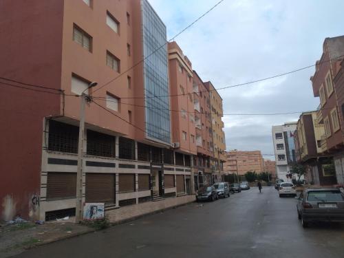 une rue urbaine vide avec des bâtiments et des voitures garés dans l'établissement appartement berkane, à Berkane