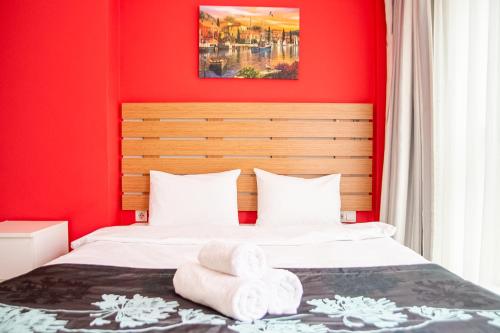ein rotes Schlafzimmer mit einem Bett mit Handtüchern darauf in der Unterkunft Fi Homes in Izmir