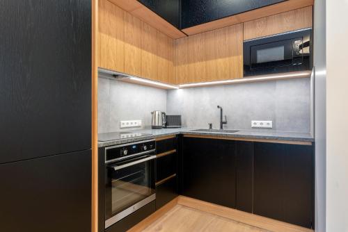 a kitchen with wooden cabinets and stainless steel appliances at TartuKodu Riia20A-8 in Tartu