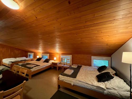 a room with three beds and a wooden ceiling at Family & Mountain Lodge C'est la Vie in Hasliberg