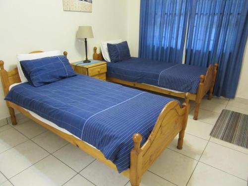 two beds in a room with blue sheets at Gretna Cottage in St Lucia