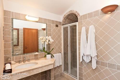 bagno con lavandino e specchio di Residence Baia delle Palme a Pula