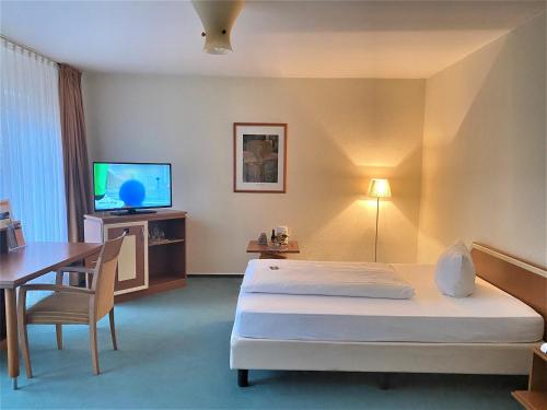 Habitación de hotel con cama, escritorio y TV. en Grothenns Hotel 3-Sterne superior en Bremen