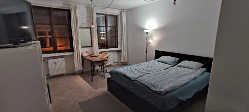 a bedroom with a bed and a table and windows at Private Apartament Wroniecka 6 in Poznań