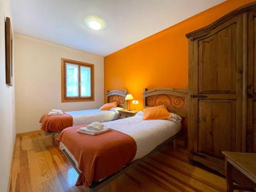 2 camas en una habitación con paredes de color naranja en Casa Ederra, en Isaba