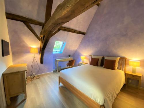 um quarto com uma cama branca num quarto com pisos em madeira em DOMAINE DES LUMIERES em Aisonville-et-Bernoville