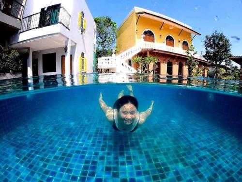 a man is swimming in a swimming pool at Aen Guy Boutique Hotel in Sukhothai