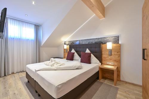 1 dormitorio con 1 cama grande con sábanas blancas y almohadas rojas en Landhaus am See Appartement LH 06, en Schwangau