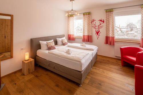 a bedroom with a large bed and a red chair at Chalet am Breitenberg Appartement CB 08 in Pfronten