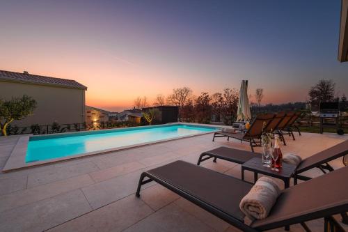 a swimming pool with chaises and chairs on a patio at Villa Oliva Muntrilj in Muntrilj