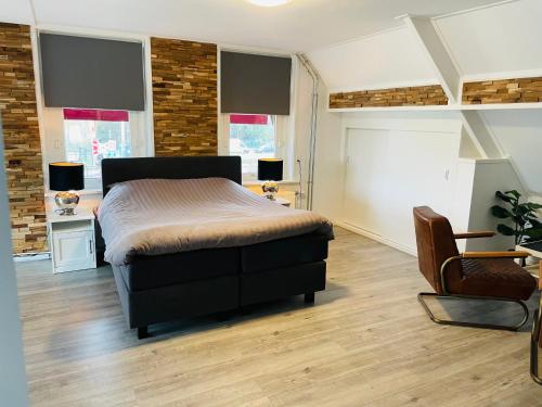 um quarto com uma cama, uma cadeira e janelas em Slapen bij de Buurvrouw em Castricum