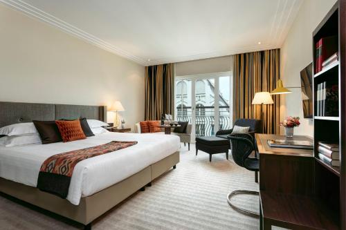 ein Hotelzimmer mit einem großen Bett und einem Schreibtisch in der Unterkunft Rocco Forte The Charles Hotel in München