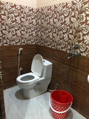 a bathroom with a toilet and a red bucket at The Taj Homes in Agra