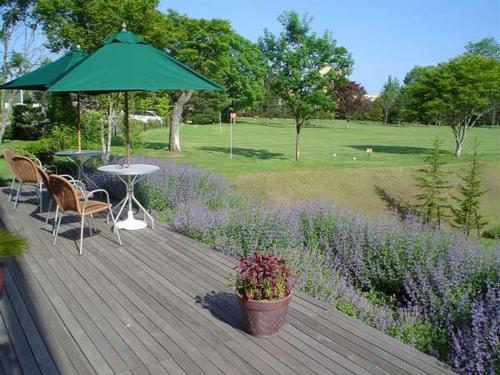 a wooden deck with a table and a green umbrella at Sanyoan in Otofuke