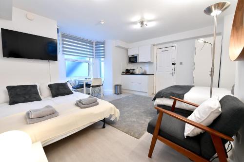 a bedroom with two beds and a living room at London Studios Very Close to Central Line Underground Shepherds Bush and Westfield Newly Refurbished in London