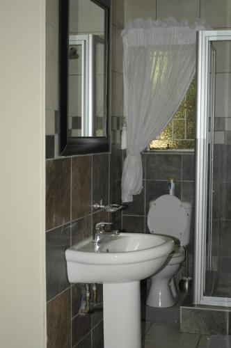 a bathroom with a sink and a toilet and a mirror at @Home Guest House in Rustenburg
