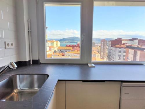 uma cozinha com um lavatório e uma janela em Vistas, recién reformado, 2 dormitorios dobles. em Santander